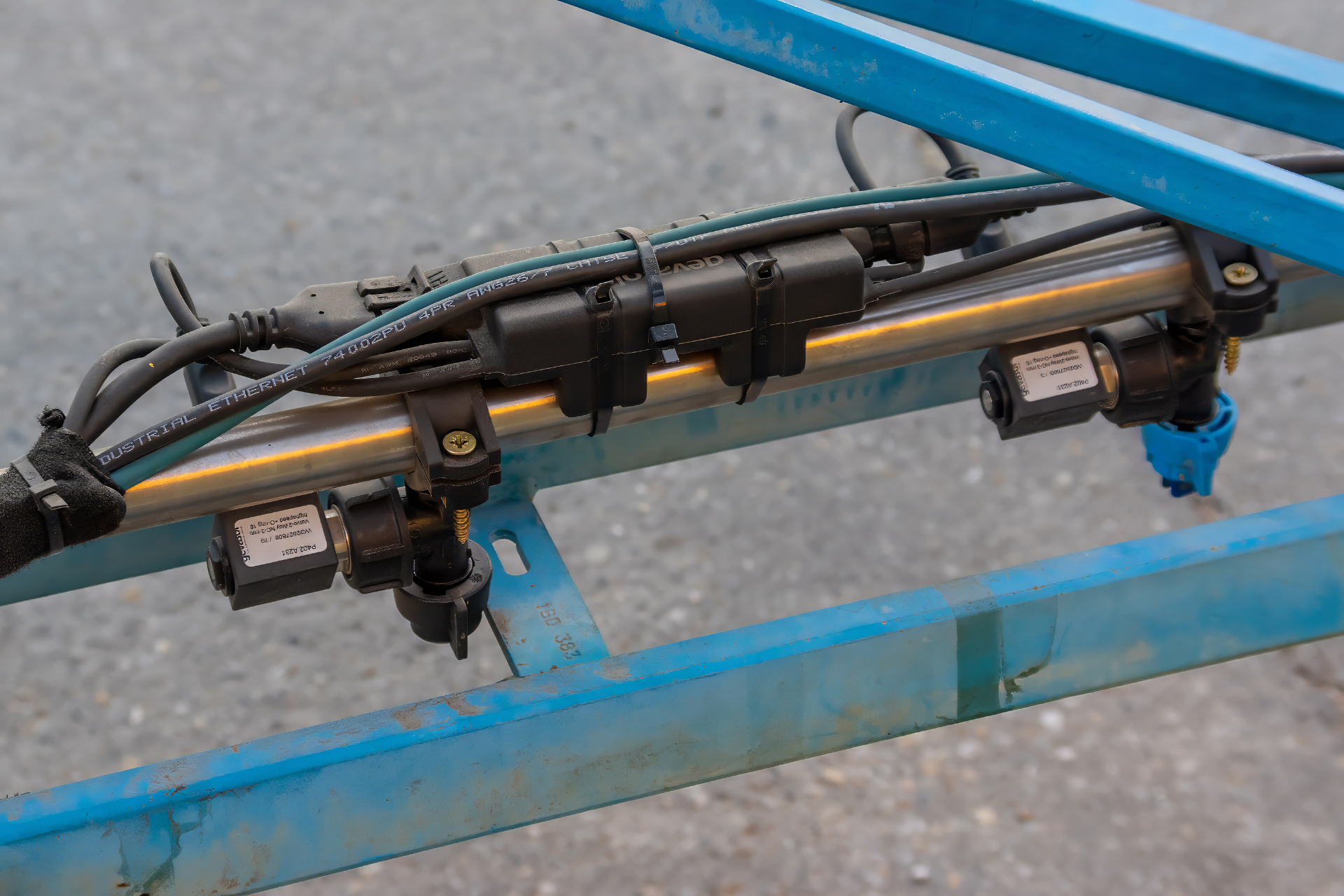 Close-up of the WeedEye RAPID high-speed solenoid valve system mounted on a spray boom